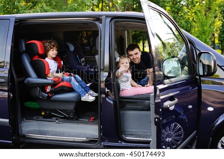 the family goes on a trip in the minivan. Father with son and daughter sitting in the salon van and smiling. Family trip