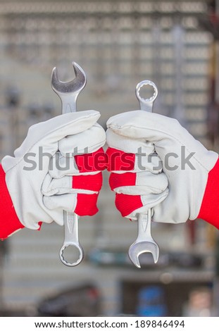 two hands in gloves with wrench