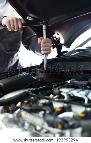 Hands with wrench on engine. Auto mechanic in car repair