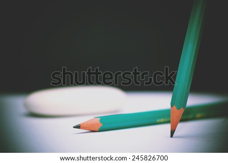 Green pencils and eraser on school board desk background.