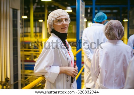 Female worker on the production line of beer factory. portrait of a woman in a white robe, standing on the background of the production line at the factory bottling of finished products
