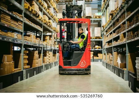 young man in working clothes, driver Reachtruck busy working on the logistics warehouse store