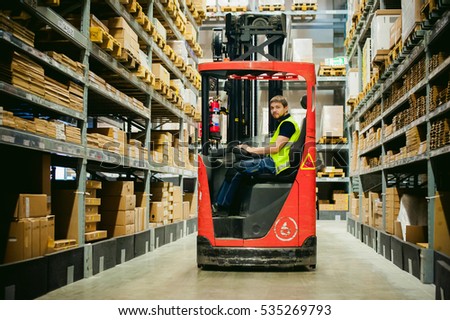 young man in working clothes, driver Reachtruck busy working on the logistics warehouse store