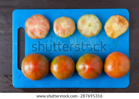 Cut tomatoes on a blue tray seen from above.