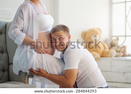 Happy family. Father listening to her pregnant wife\'s tummy.