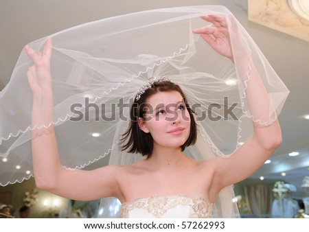 Portrait of young girl trying on bridal veil in wedding store