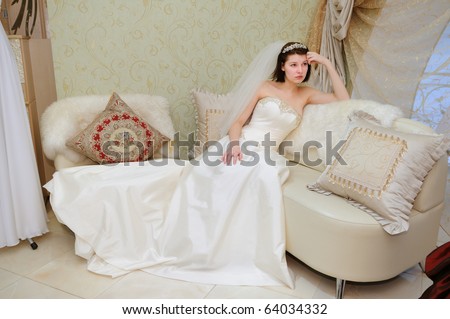 stock photo Future bride in wedding dress sitting on sofa at bridal shop