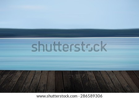 Empty wooden table with blur sea on background.