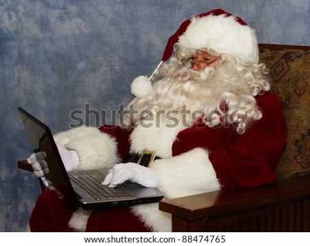 A thoroughly modern Santa claus checks his list on his laptop computer