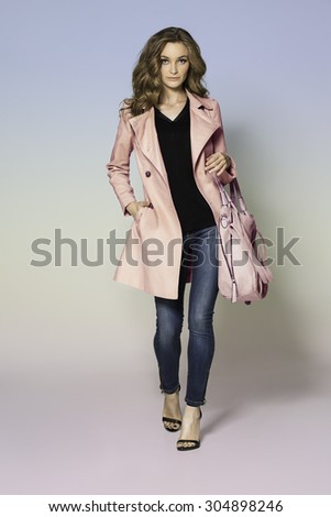 Attractive blonde beauty with elegant handbag pink coat