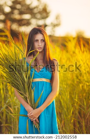 Young girl standing on a wheat field with sunrise