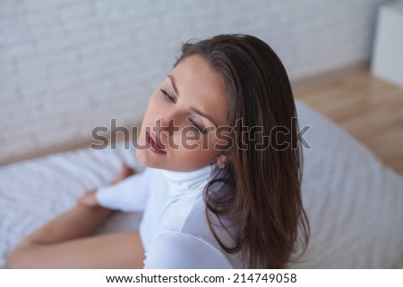 Woman in underwear is lying in the bed with white bed linen, white background