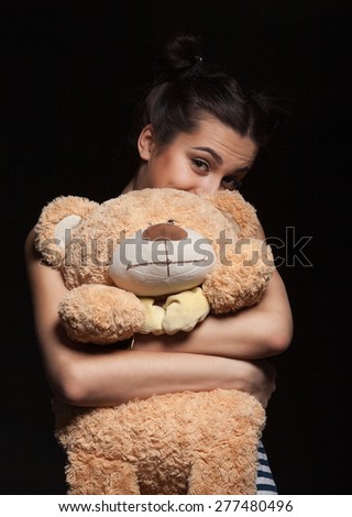 portrait of attractive caucasian smiling woman brunette with bear isolated on black studio shot