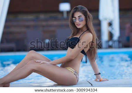 woman taking sunbath near swimming pool. beautiful woman on a tropical beach on a chaise lounge. Woman lying in a deck-chair in a hotel and enjoying sun. Young beautiful woman outdoors on the sunbed