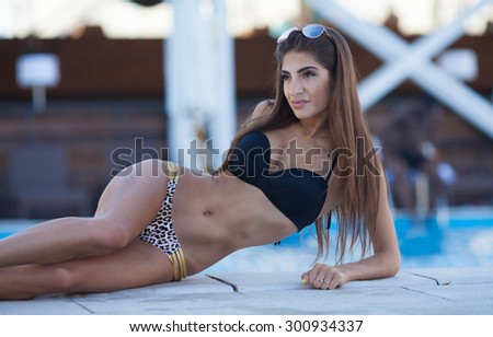 woman taking sunbath near swimming pool. beautiful woman on a tropical beach on a chaise lounge. Woman lying in a deck-chair in a hotel and enjoying sun. Young beautiful woman outdoors on the sunbed
