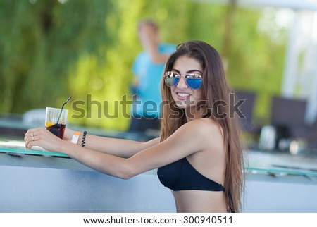 beautiful woman in orange bikini and sunlasses sitting in swimming pool with cocktail. Fashionable portrait. Elegant woman in a bikini.