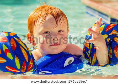 2 year old boy swimming in a pool with a flotation device--image taken outdoors using natural light (Reno, Nevada, USA)