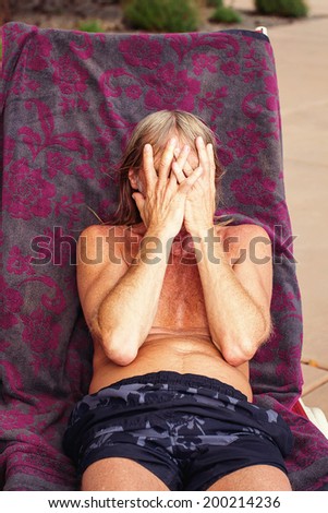 A 61 year old man sunbathing at the swimming pool -- image taken outdoors using natural light  (Reno, Nevada, USA)
