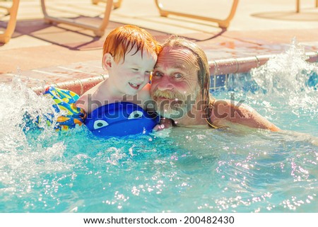 Man playing with his 2 year old grandson in the pool -- image taken in Reno, Nevada, USA