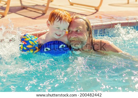 Man playing with his 2 year old grandson in the pool  -- image taken in Reno, Nevada, USA