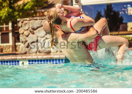 Man playing with his niece in the swimming pool -- image taken outside in Reno, Nevada, USA