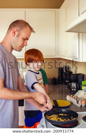Man cooking eggs in his kitchen with his 4 year old son -- image taken in Reno, Nevada, USA