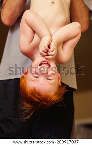 Father holding his 2 year old son upside down -- image taken in Reno, Nevada, USA