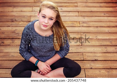 Tween girl lying on a wooden bridge at the park -- image taken outdoors at Rancho San Rafael Park in Reno, Nevada, USA