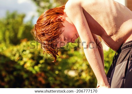 7 year old boy playing in the sprinkler on a hot day -- image taken outdoors in Reno, Nevada, USA