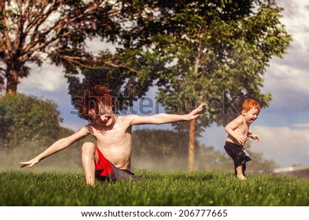 Two young brothers playing in the sprinklers on a hot day -- image taken outdoors in Reno, Nevada, USA