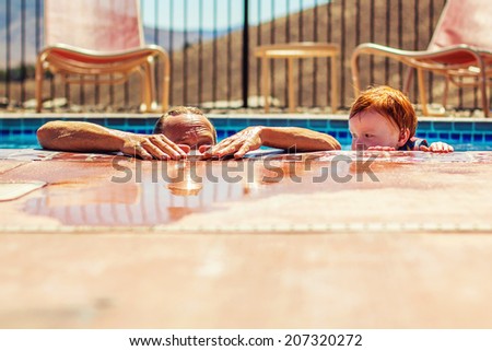 3 year old boy playing in the swimming pool with his grandfather, with his life jacket on -- image taken outdoors in Reno, Nevada, USA