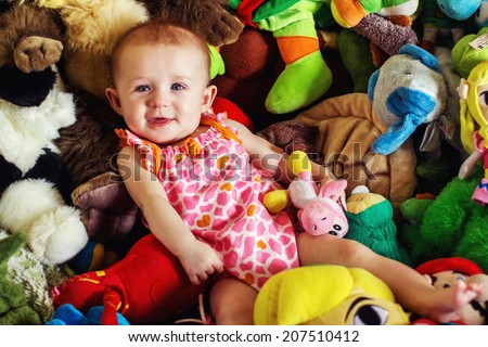 4 month old baby girl lying on a pile of stuffed toys -- image taken in Reno, Nevada, USA