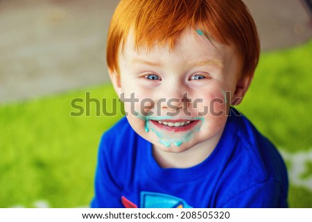 2 year old boy sitting on his patio with blue ice cream all over his face -- image taken in Reno, Nevada, USA
