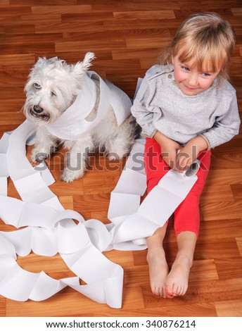 Naughty child and white schnauzer puppy dog sitting on a floor and playing with  roll of toilet paper