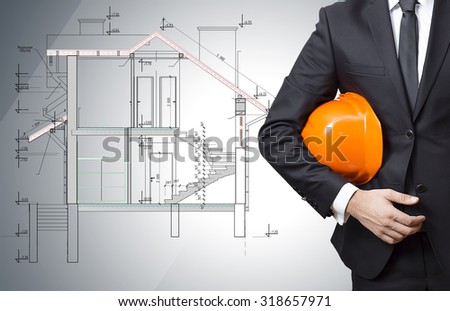 the architect  hold  a helmet in his hand, on the blueprint background.