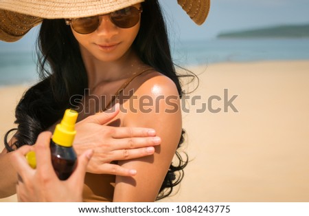 Close - up of Sexy asian woman are Spray Sunscreen , lotion or sunblock to body for prevent UV rays from sunlight Before the sun bathing in the summer or Vacation with sea and bluesky bckground