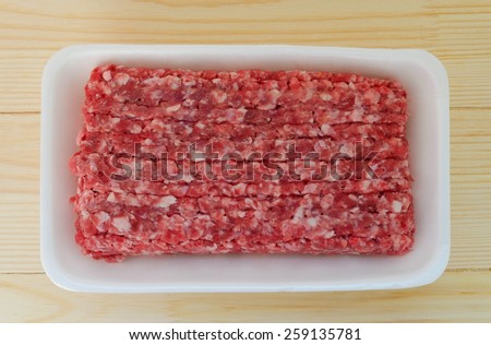 Fresh minced meet in package over wooden background