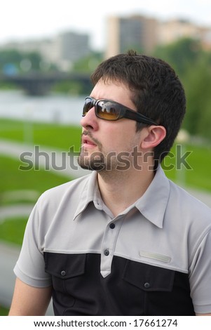 Young man with his mouth open looking up at something in astonishment on city view background