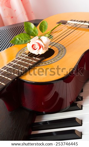Pink rose on guitar and piano keyboard.