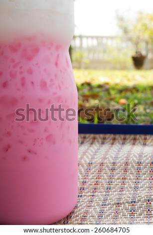 Ice strawberry milk in plastic bottle. On mat in outdoor.