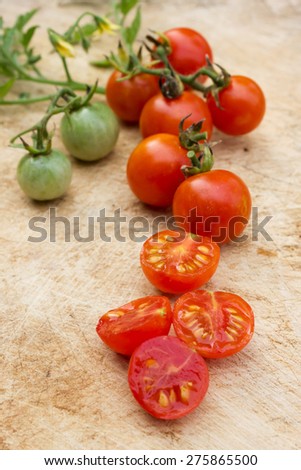 Fresh ripe cherry tomato and sliced tomatoes on wooden board.