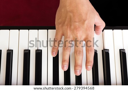 Man\'s hand playing piano. Top view.