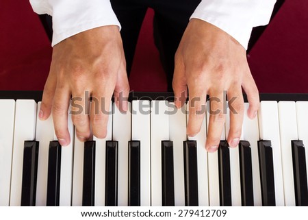 Man's hand playing piano. Top view.