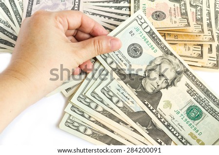 Woman's hand hold a twenty dollar bill on white background. Bills are background.
