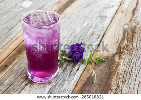 Juice of Butterfly pea with lemon and ice in glass on wooden table. Herb drink for refreshment.