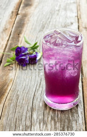 Juice of Butterfly pea with lemon and ice in glass on wooden table. Herb drink for refreshment.