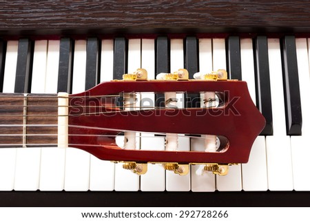 Closeup guitar neck on piano keys. Abstract and art background.