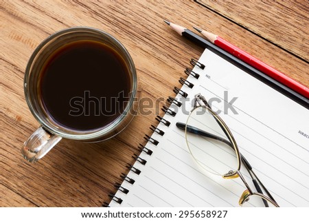 Concept background of business and education. Black coffee, eye glasses and notebook with pencil. Top view.