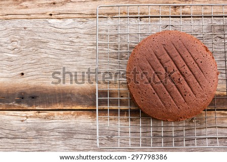 Chocolate cake on baking rack over wooden table. Top view.