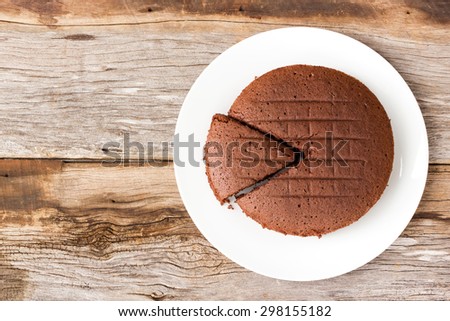 Chocolate cake on white plate. Over wooden table. Top view.